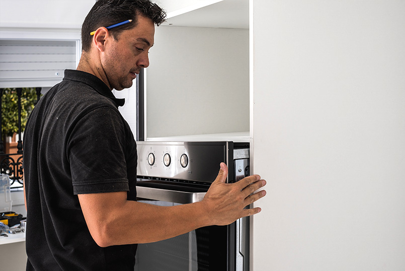 Planning And Installing Your New Kitchen Handyman working on an oven cabinet